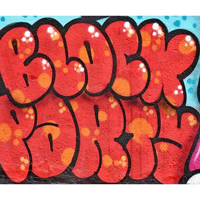 colorful orange graffiti spelling out block party on brick wall.