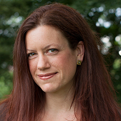 host Cynthia Graber woman with long red hair with leaves in the background.