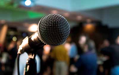 close up of the front of a microphone with blurry crowd in the background