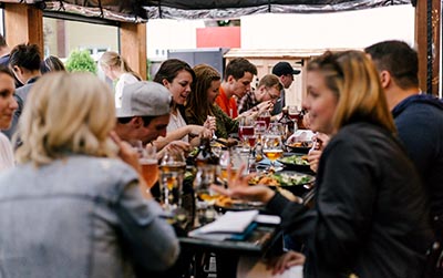 large table with diners sitting around talking, smiling, and eating.